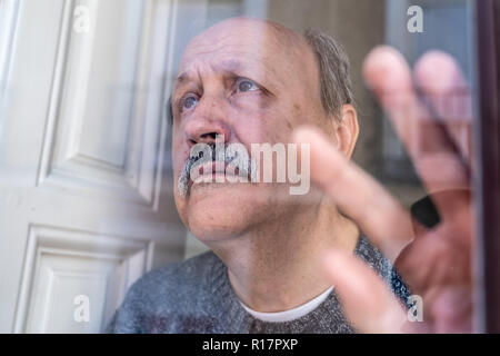 Old man à travers la fenêtre un sentiment de confusion et de dépression seule à la maison de retraite Le vieillissement dans la démence d'Alzheimer et de la notion de veuf. Banque D'Images
