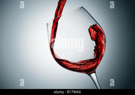 Verser le vin rouge dans le verre, fond gris Banque D'Images