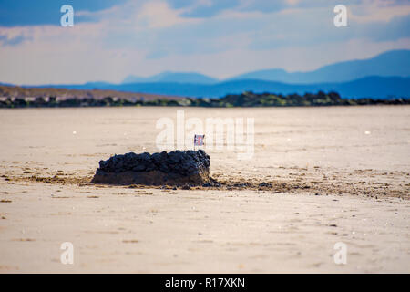 Château de sable/boue château surmonté d'un petit drapeau tête de mort sur la plage. Les montagnes d'Snowdoncan est visible en arrière-plan. Prestatyn, ni Banque D'Images