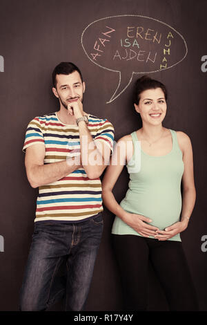 Deux jeunes femmes enceintes de penser à des noms pour leur enfant à naître et les écrire sur un tableau noir Banque D'Images