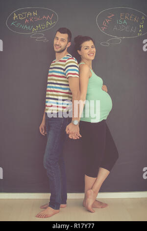 Deux jeunes femmes enceintes de penser à des noms pour leur enfant à naître et les écrire sur un tableau noir Banque D'Images