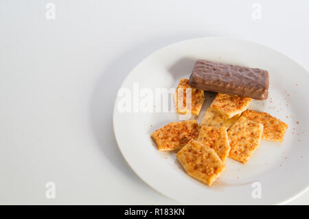 Biscuits aromatisés sur une plaque avec un biscuit chocolat sur fond blanc Banque D'Images