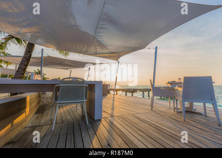 Restaurant de plage, Coucher de soleil extérieur scène, chaises et table, modern tropical resort ou à l'extérieur de l'hôtel Banque D'Images