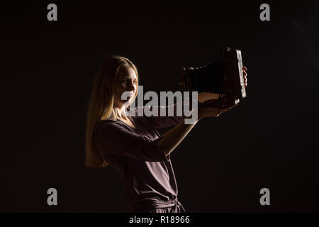 Portrait Portrait blanc modèle féminin. Belle fille, de longs cheveux blonds de prendre une photo avec l'appareil photo. Woman posing studio shot on a black backgrou Banque D'Images