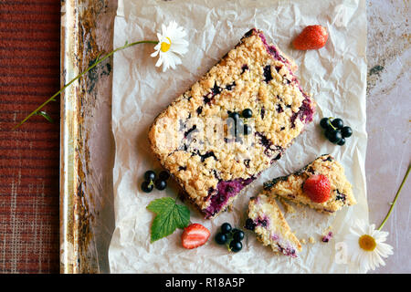 Vue de dessus de cassis, fraise et cottage gâteau crumble sur du papier sulfurisé et fond rustique Banque D'Images