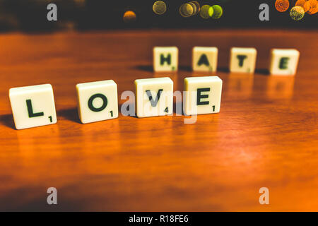 L'amour et la haine énoncées avec pièces de scrabble sur une table en bois Banque D'Images