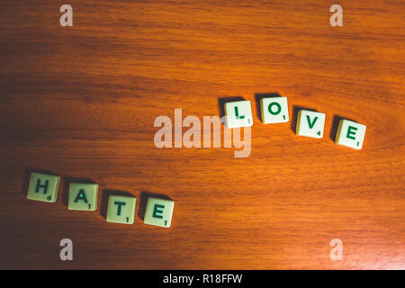 L'amour et la haine énoncées avec pièces de scrabble sur une table en bois Banque D'Images