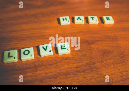 L'amour et la haine énoncées avec pièces de scrabble sur une table en bois Banque D'Images