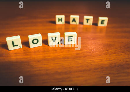 L'amour et la haine énoncées avec pièces de scrabble sur une table en bois Banque D'Images