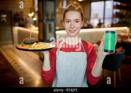 Jolie serveuse avec ordre de prix client montrant des smartphone en combo Banque D'Images