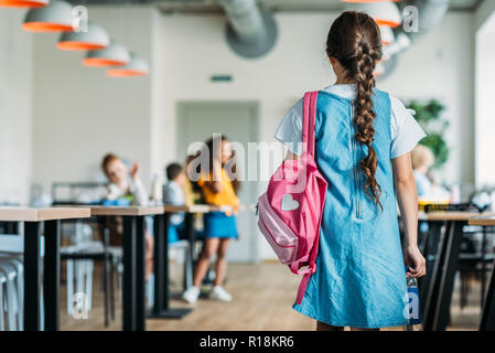 Vue arrière de la petite lycéenne en tenue à l'école à pied cafétéria Banque D'Images