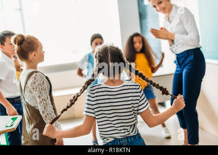 Groupe de camarades multiethnique debout autour d'enseignant à la classe Banque D'Images