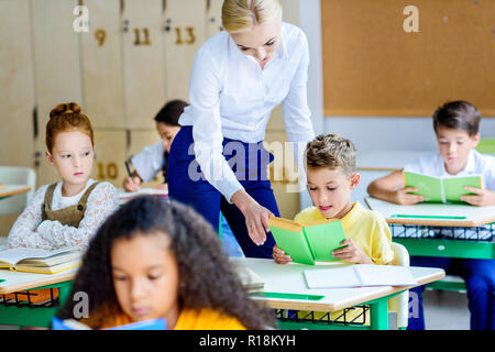 Belle vérifier combien d'enseignants enfants lire des livres pendant la leçon Banque D'Images