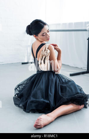 Beaux jeunes offres ballerine holding les pointes et assis dans ballet studio Banque D'Images