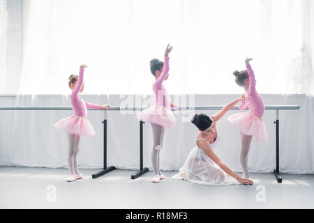 Vue latérale du jeune professeur de ballet l'exercice avec les enfants dans l'école de ballet Banque D'Images