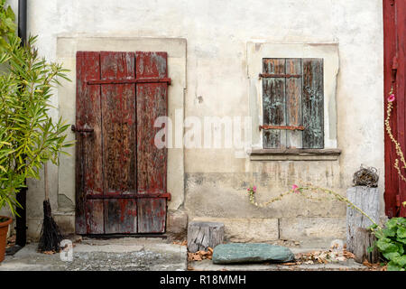 Vieille maison rustique vintage avant avec porte massive en bois et volets aux fenêtres et des fleurs sur les côtés Banque D'Images