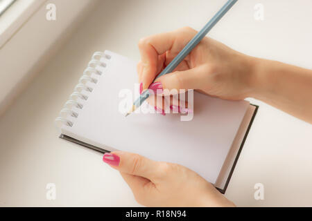 La jeune fille à la fenêtre maintenant un ordinateur portable, close-up Banque D'Images