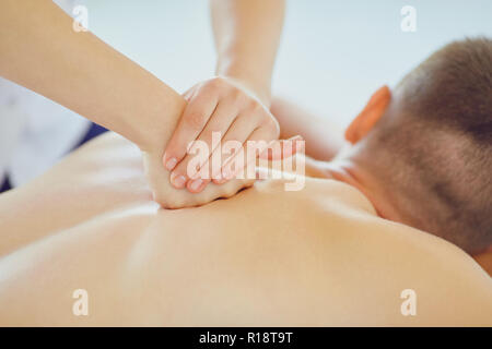 Massage dos pour un homme allongé sur la table dans le salon spa Banque D'Images