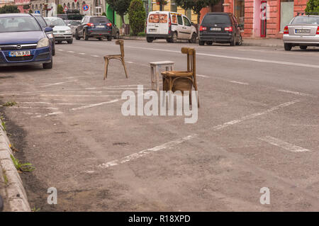 SIGHISOARA, ROUMANIE - 1 août 2018 : Des chaises en bois rustique ancien marquage des places de stationnement dans la rue Banque D'Images