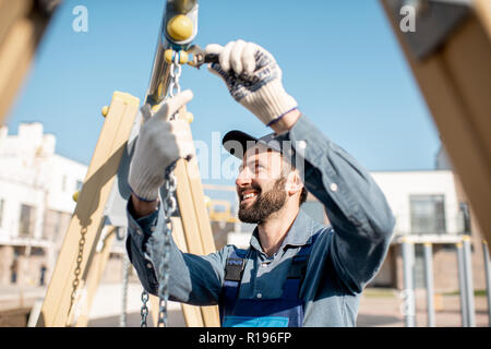 Beau workman en uniforme sur l'aire de rotation de montage à l'extérieur Banque D'Images