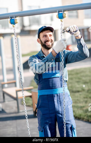 Beau workman en uniforme sur l'aire de rotation de montage à l'extérieur Banque D'Images