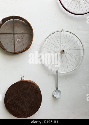 Les tamis, les roues de bicyclette et une louche accrochée sur un mur blanc d'une traditionnelle Lefka Chypre chambre à des fins de décoration Banque D'Images