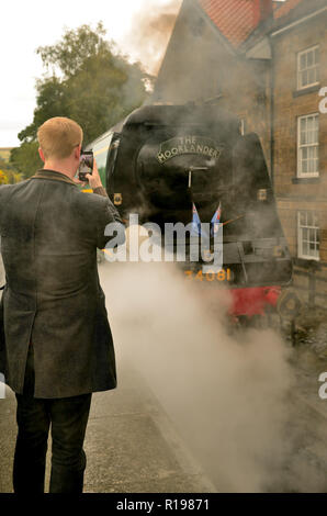 Un passager utilisant un téléphone portable pour photographier la bataille d'Angleterre pacifique classe No 34081 de l'Escadron '92' à Grosmont. Banque D'Images