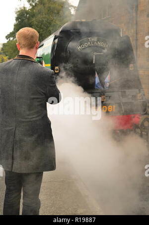 Un passager utilisant un téléphone portable pour photographier la bataille d'Angleterre pacifique classe No 34081 de l'Escadron '92' à Grosmont. Banque D'Images