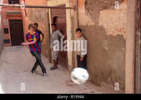 18-04-11. Marrakech, Maroc. Garçon anglais jouant au football avec les garçons marocains dans une ruelle dans la médina. Photo © Simon Grosset / Q Photography Banque D'Images