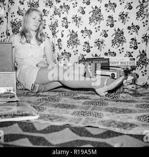 Un des années 1970 Photographie noir et blanc montrant une jeune fille assise sur le sol de sa chambre à écouter les disques vinyles sur un disque. Les enregistrements par Johnny Mathis et George Shearing sont visibles. Banque D'Images