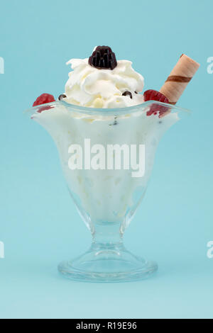 La crème glacée avec des framboises dans un beau verre sur un fond bleu Banque D'Images