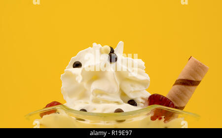 La crème glacée avec des framboises dans un beau verre libre sur un fond jaune Banque D'Images