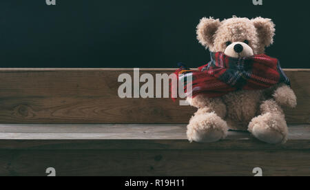 L'hiver, le froid, la solitude. Ours en peluche avec écharpe assis seul sur un banc en bois, bannière, copy space Banque D'Images