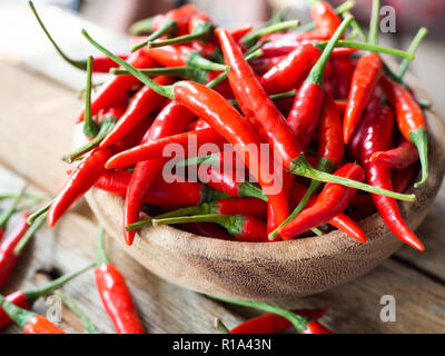 Piments rouges frais dans un bol en bois sur table en bois Banque D'Images