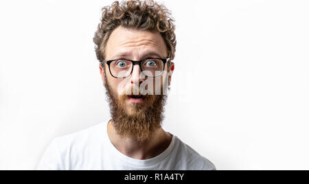 Surpris caucasian man avec les cheveux bouclés et la barbe en regard de surprise au huis clos Banque D'Images