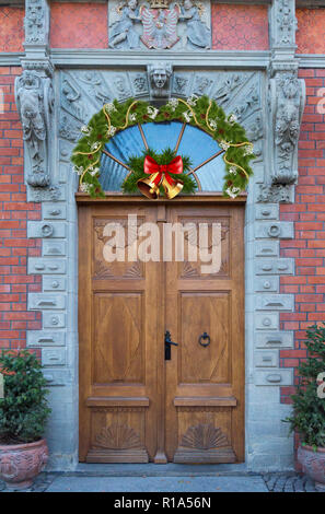 Au-dessus de la belle porte en bois, se trouve une couronne de Noël et des cloches. Banque D'Images