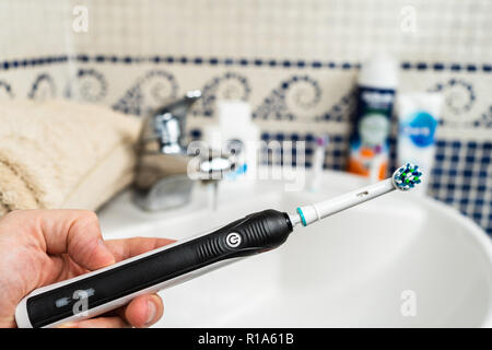 Brosse à dents electrique rechargeable avec une poignée noire et cinq têtes de brosse à dents.fond bleu clair. Banque D'Images