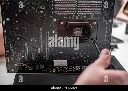 Le spécialiste de l'installation d'un refroidisseur sur le nouveau processeur dans le contexte d'une carte mère Asus rog crosshair vii héros. Banque D'Images
