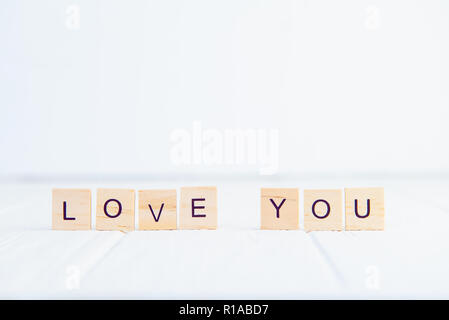 Message je t'aime en toutes lettres dans des blocs de bois debout sur une table en bois blanc. Valentines Day background. Concept de simplicité. Focus sélectif. Copy space Banque D'Images