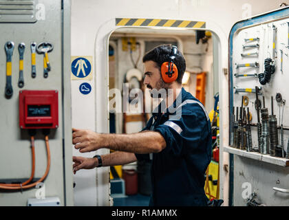 Officier mécanicien de marine dans la salle de commande des moteurs des machines. Le travail des marins. Il démarre ou arrête le moteur principal du navire Banque D'Images