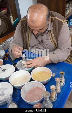 Un peintre de sable jordanien dans Rajif, Jordanie la peinture avec du sable. Dans un magasin de souvenirs près de Petra. Banque D'Images