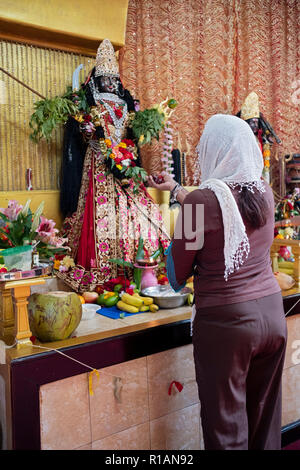 Un dévot hindou propose des fruits à la déesse Kali dans un temple hindou de Shakti dans le Queens, New York. Banque D'Images