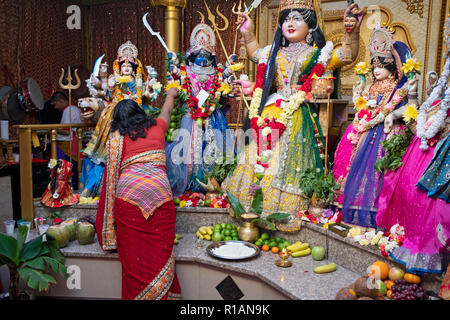 Un hindou dévot porte les fleurs à la déesse Kali dans un temple hindou de Shakti dans le Queens, New York. Banque D'Images