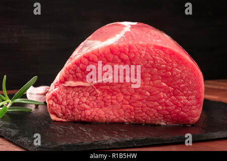 Une photo de l'oeil de boeuf rond, matière, coupe avec le romarin, l'ail et le poivre, sur un fond noir avec copie espace Banque D'Images