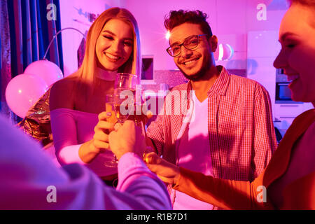 Groupe de jeunes de célébrer le Nouvel An et de trinquer avec les verres de champagne ayant house party Banque D'Images