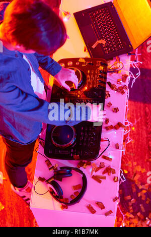 Au-dessus de l'homme de jouer de la musique sur DJ mixer au bureau avec ordinateur portable et confetti Banque D'Images