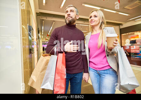 Portrait of happy couple shopping in mall à la fenêtre à l'affiche et souriant Banque D'Images