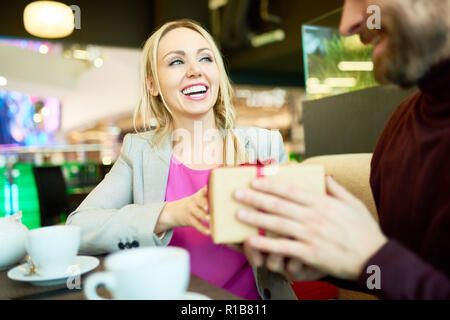 Portrait de couple échange présente à table dans un café, l'accent sur happy woman holding gift box Banque D'Images