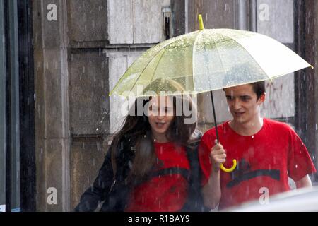 Couple heureux sous la pluie parapluie Banque D'Images