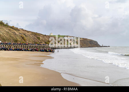 Folkestone, Kent, Angleterre. 11 novembre 2018. Les gens de la mer, sous un ciel gris, de regarder un portrait de sable de Wilfred Owen lentement été emportées par la marée montante. 100e anniversaire de la fin de la première guerre mondiale, le souvenir de l'événement Dimanche, 'Pages de la mer'. Banque D'Images